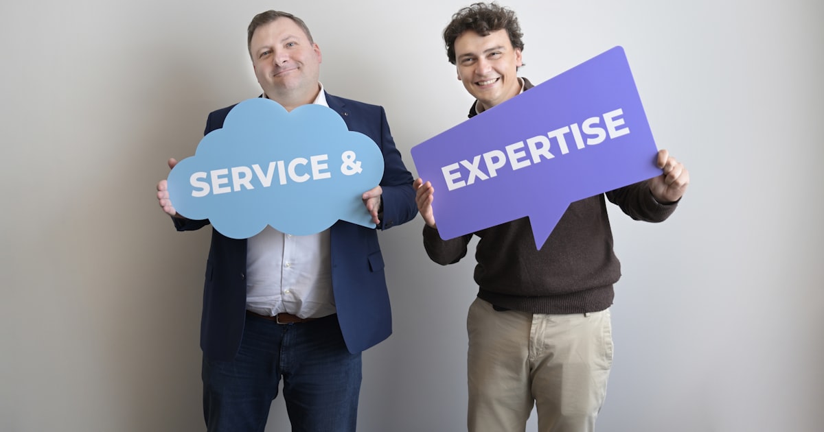 Two smiling men holding "service &" and "expertise" signs.