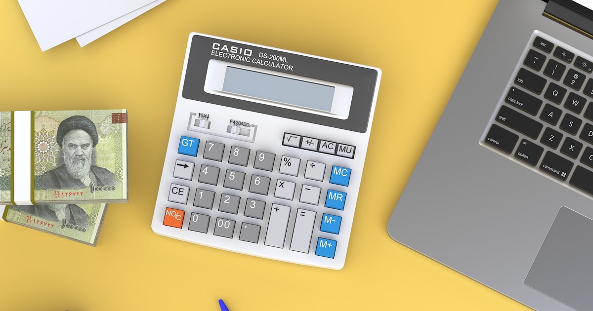 A calculator sitting on top of a desk next to a laptop