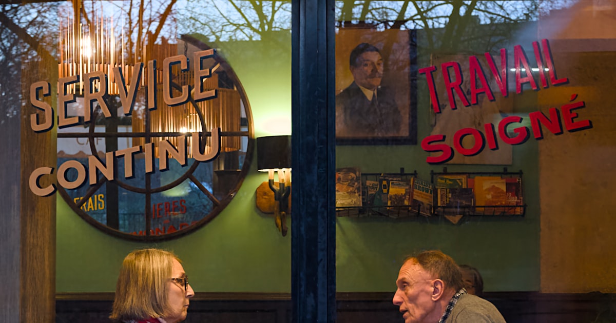 Two people talking at a table inside a cafe