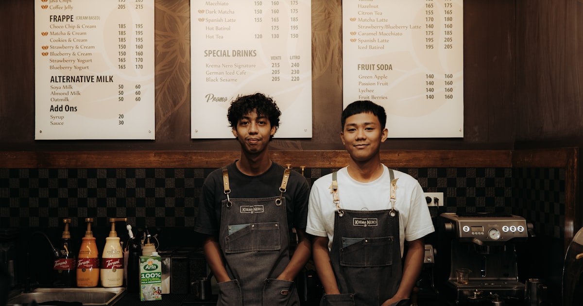 Two baristas smiling behind a counter