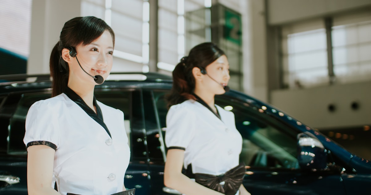 Two women in uniform standing near a car