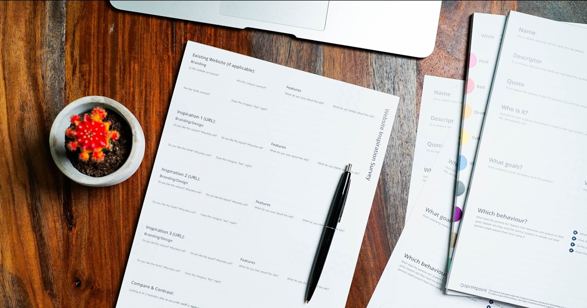 A wooden table topped with papers and a pen
