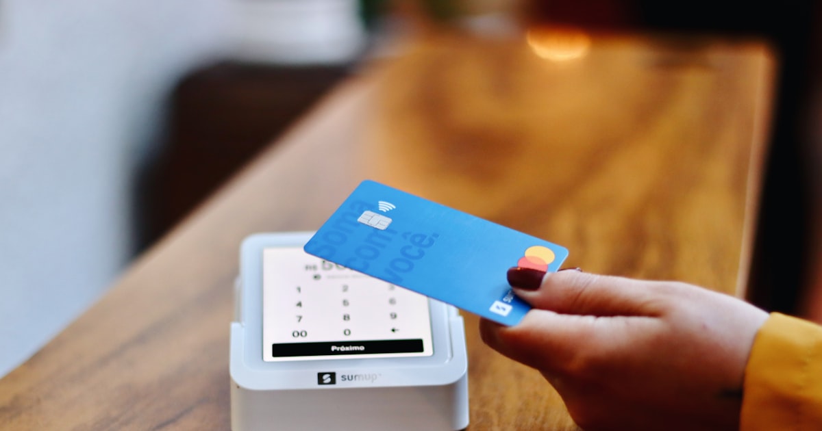 A person holding a credit card in front of a machine
