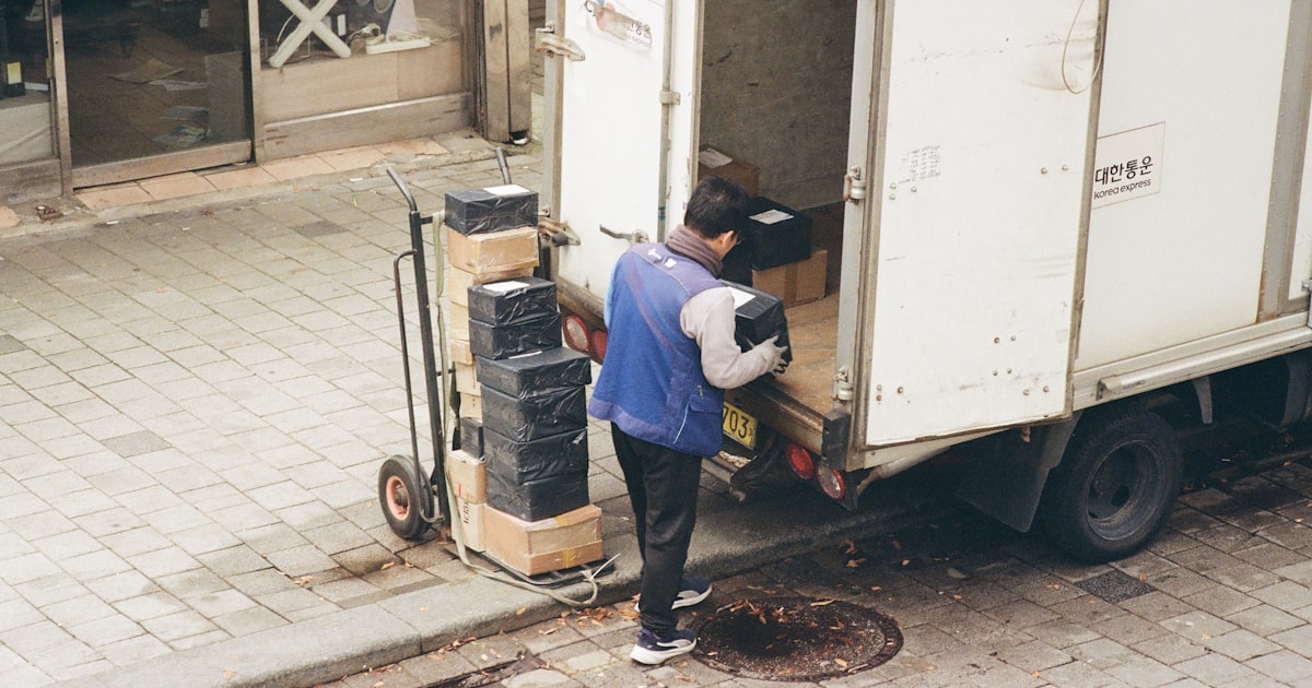 Man loading boxes from a truck onto a dolly.