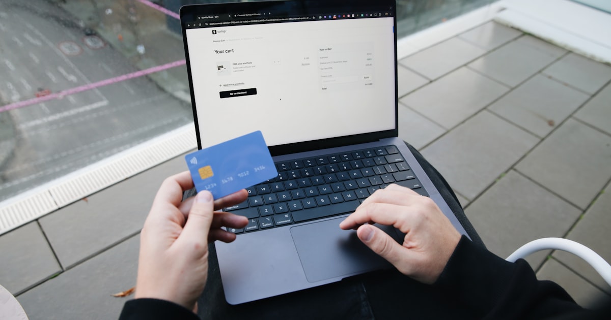 A person sitting in a chair with a laptop and a credit card