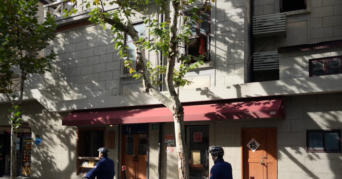 Two people riding electric scooters on a street.
