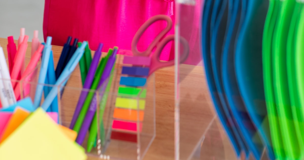 Woman in pink holding colourful files and office supplies