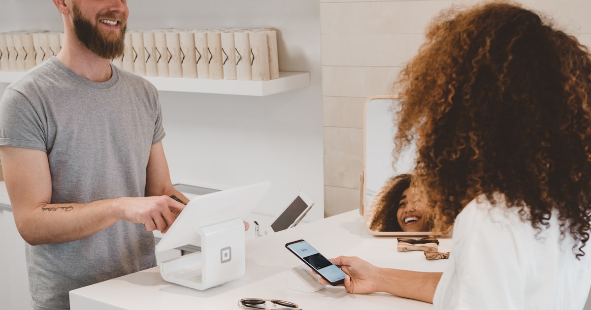 man in grey t-shirt smiling to woman at a counter