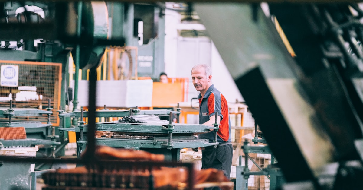 A man in a grey and red shirt operating industrial machinery in a factory