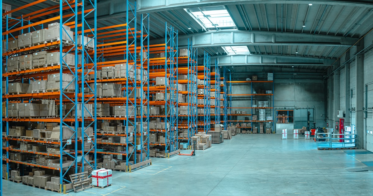 Tall blue metal shelving units filled with cardboard boxes in a large warehouse