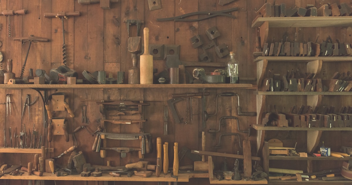 assorted hand tools on a brown wooden shelf