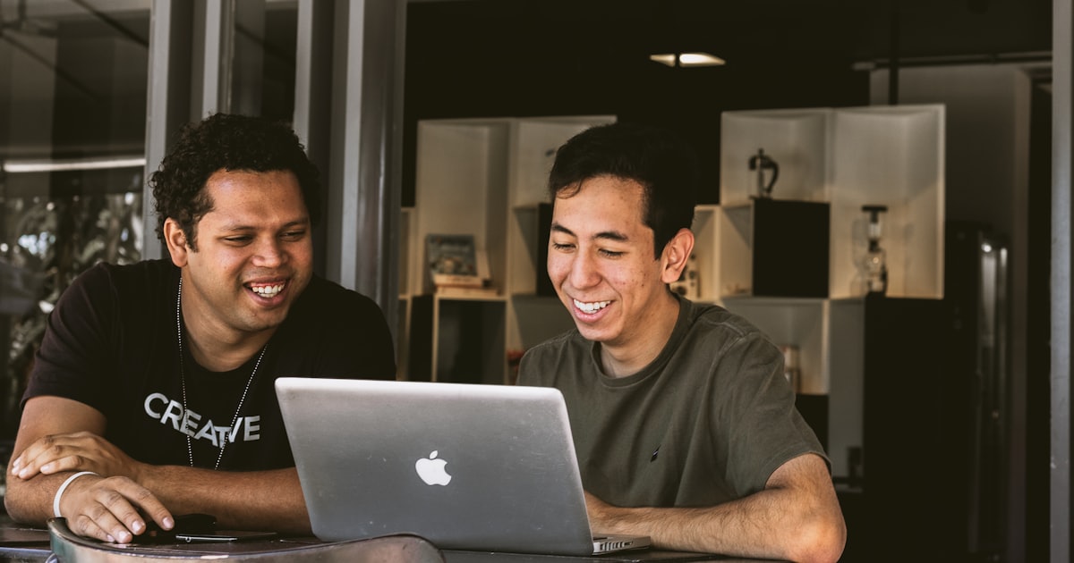 two smiling men looking at a laptop