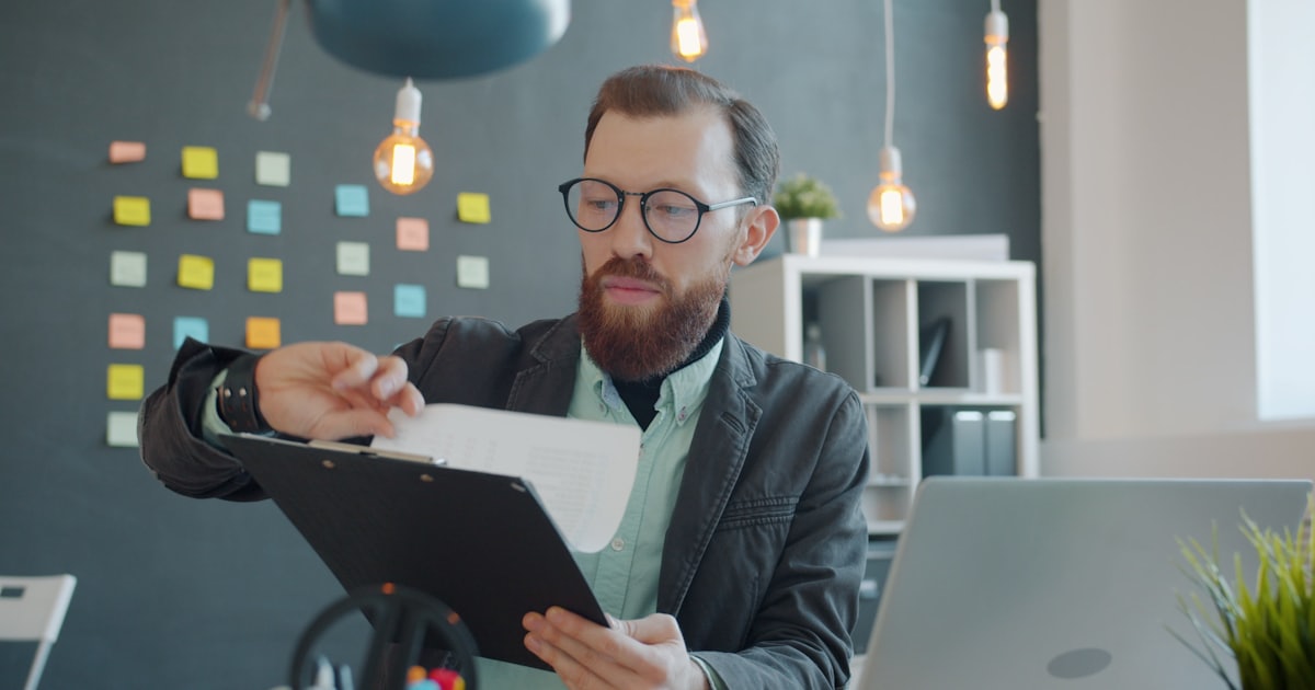 Man in glasses reviewing documents at a desk