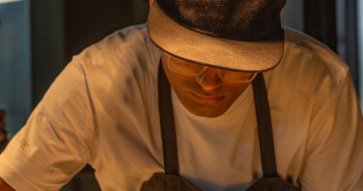 A man in a hat is preparing food on a table