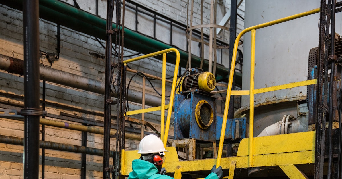 a man in a green coverall climbing a yellow ladder