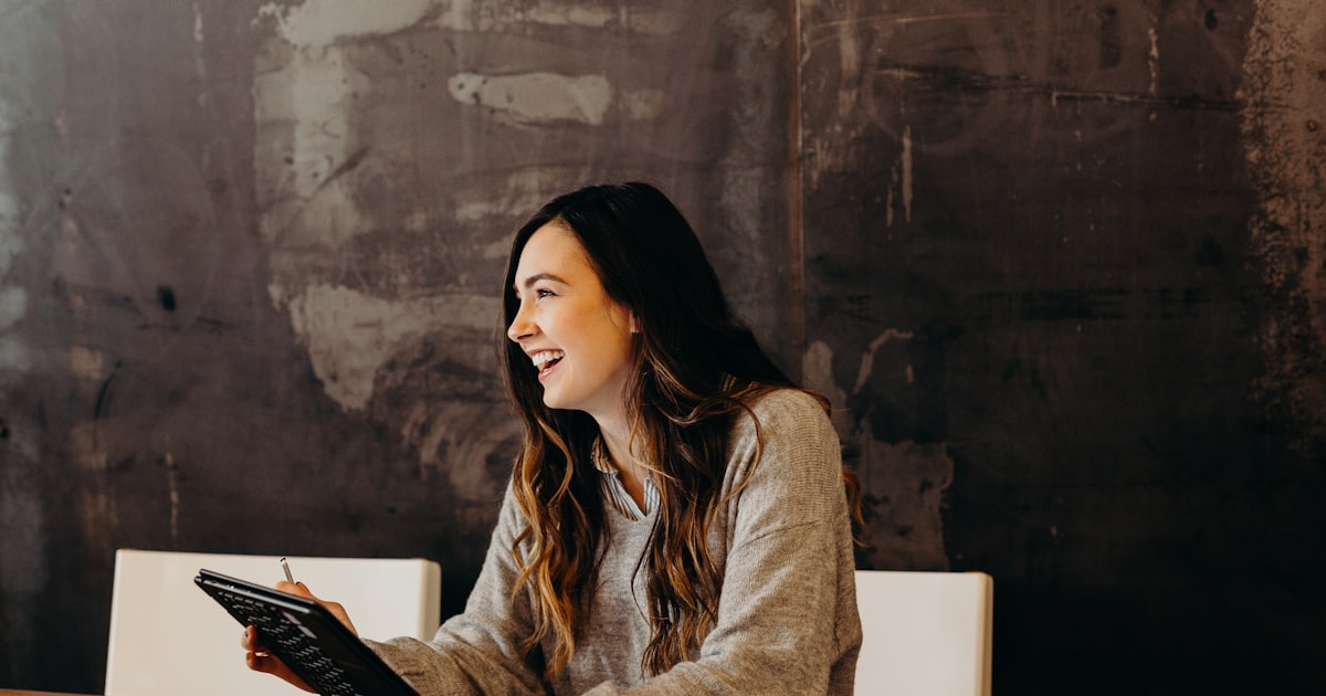woman sitting around table holding tablet