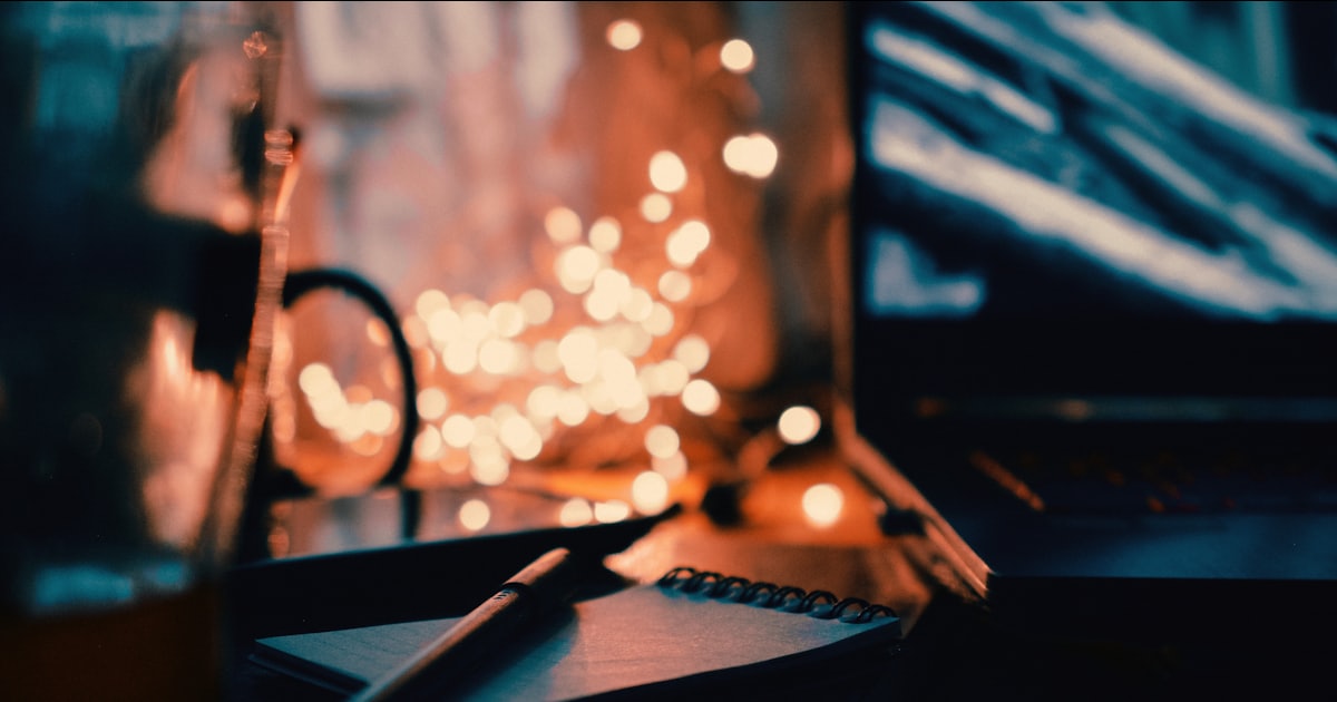 a desk with a pen, notebook and a laptop on it