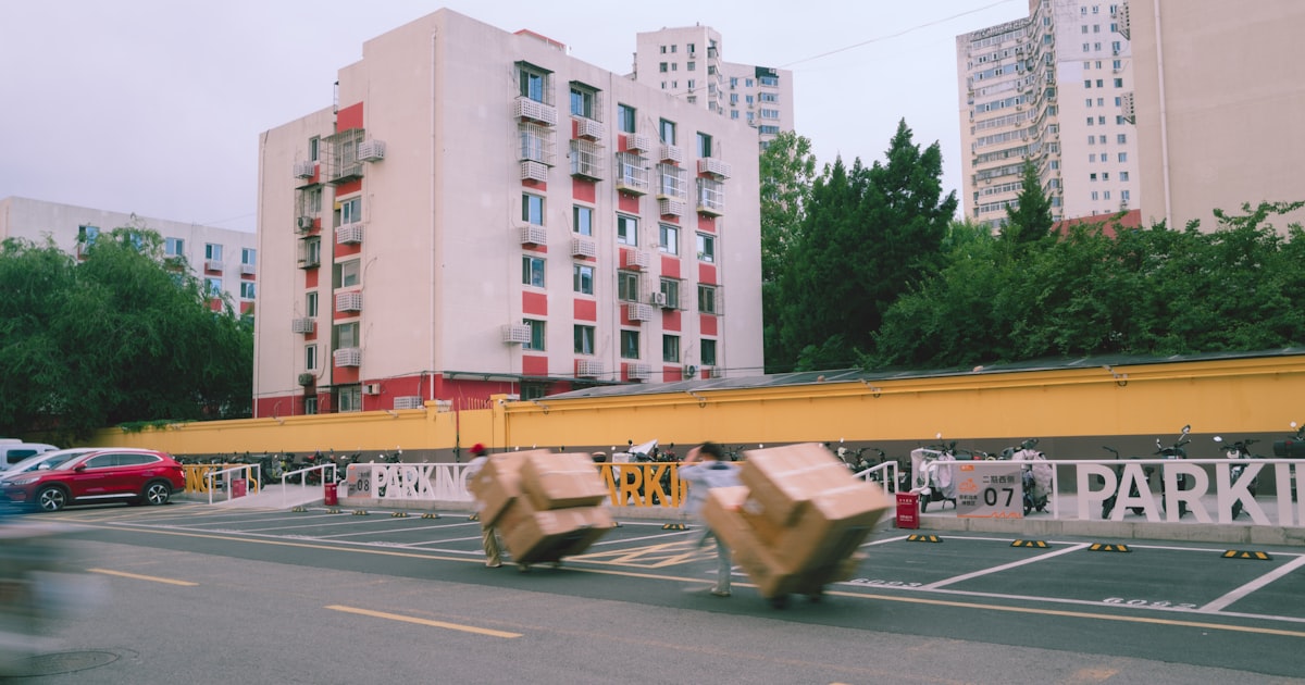 Cardboard boxes on wheels moving past apartment buildings.