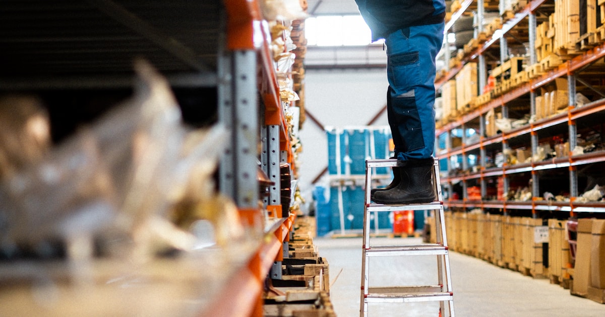 A worker on a ladder in a warehouse