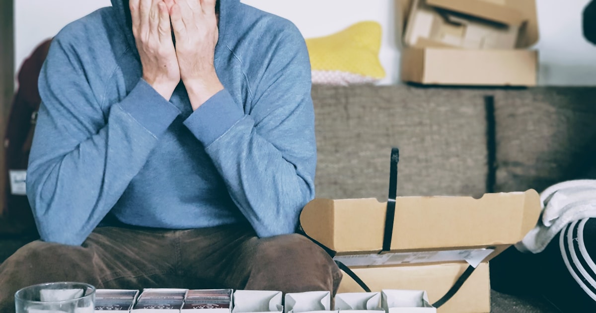 Man covering face with both hands while sitting on bench