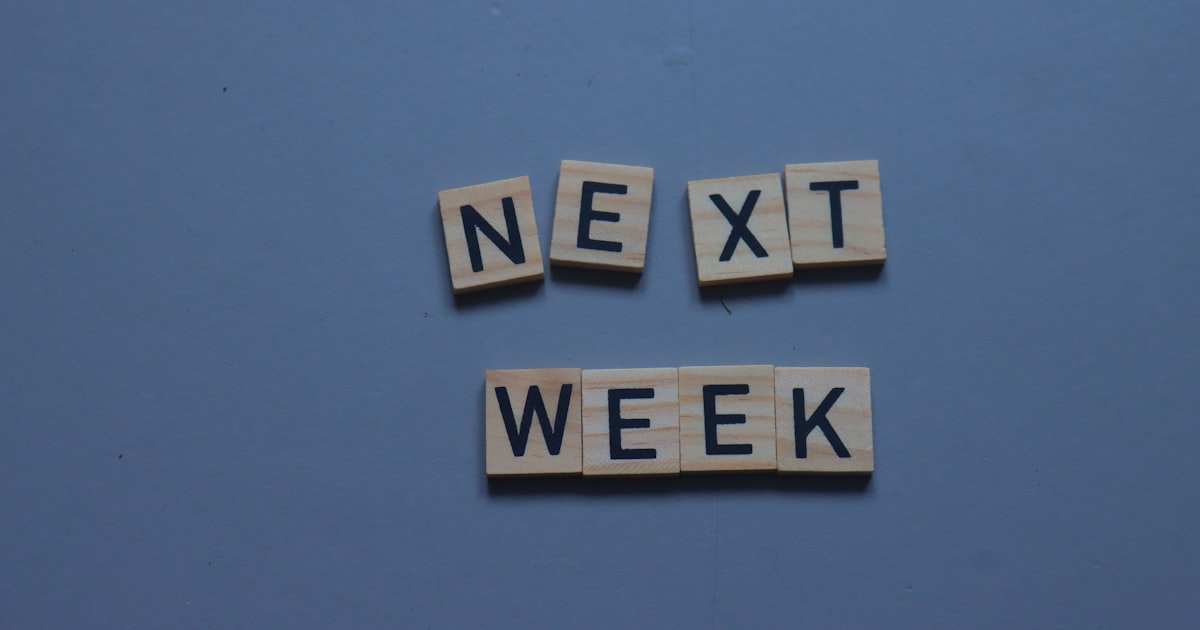Scrabble tiles spelling the word next week on a blue background