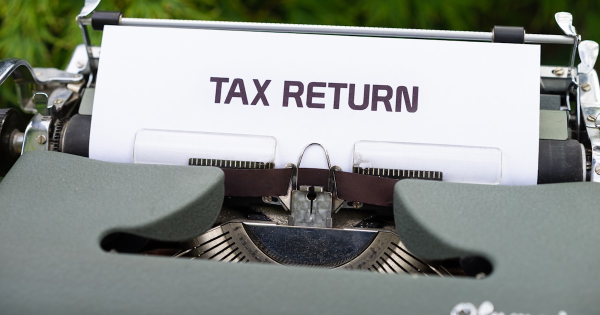 A close up of a typewriter with a tax return sign on it