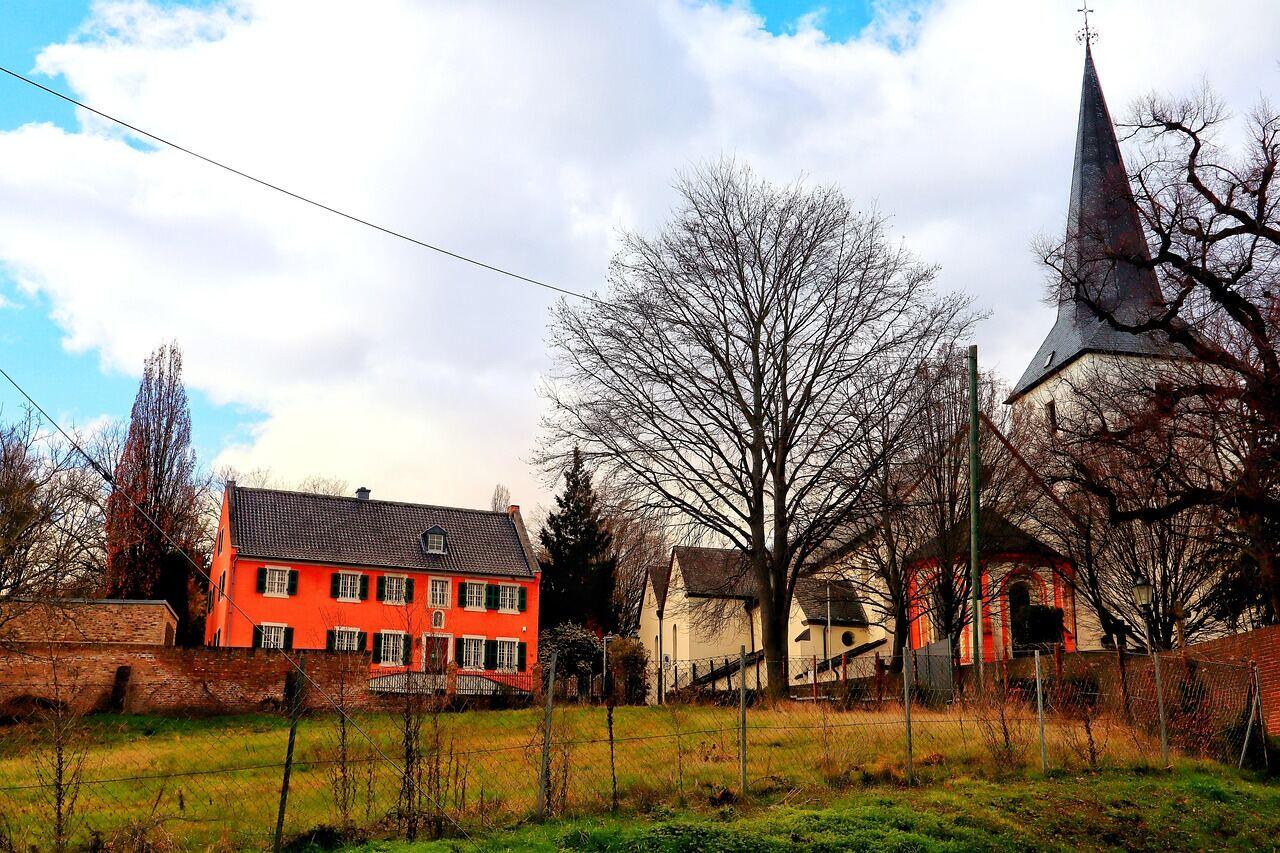 A modest parish hall standing beside a church with a tall spire