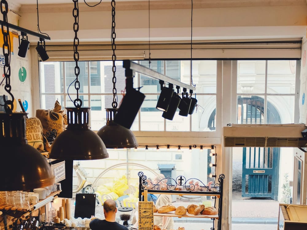 Interior of The Golden Crumb bakery — warm wood tones, chalkboard menu, morning light through the window