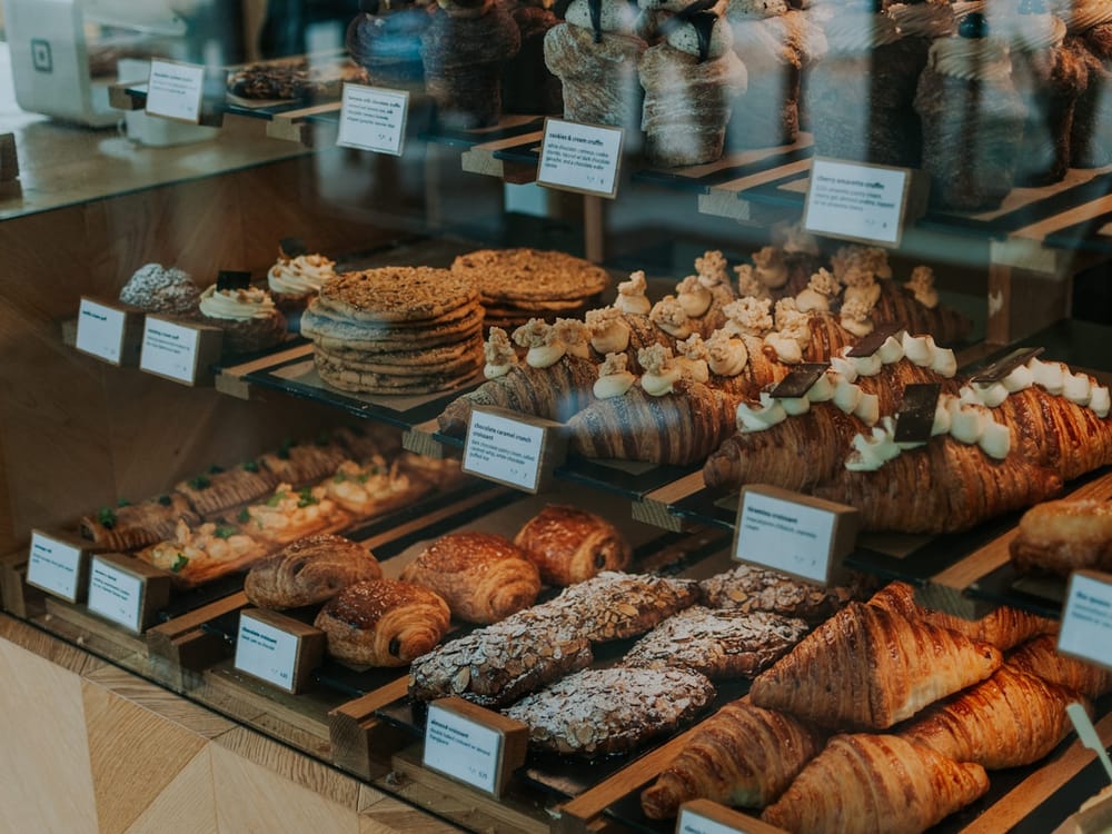 Morning pastry case with croissants, Danishes, and morning buns in warm light