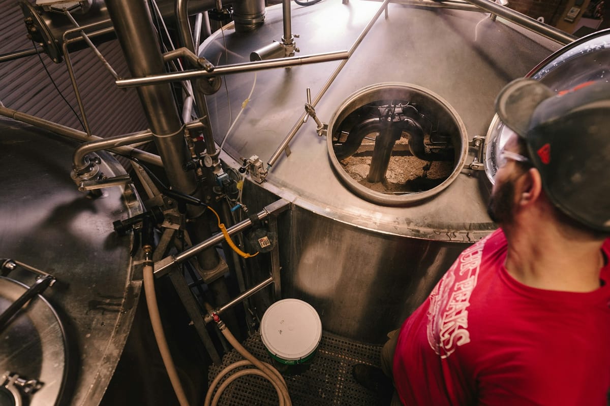 A brewer at work beside the stainless fermentation tanks in the brew house