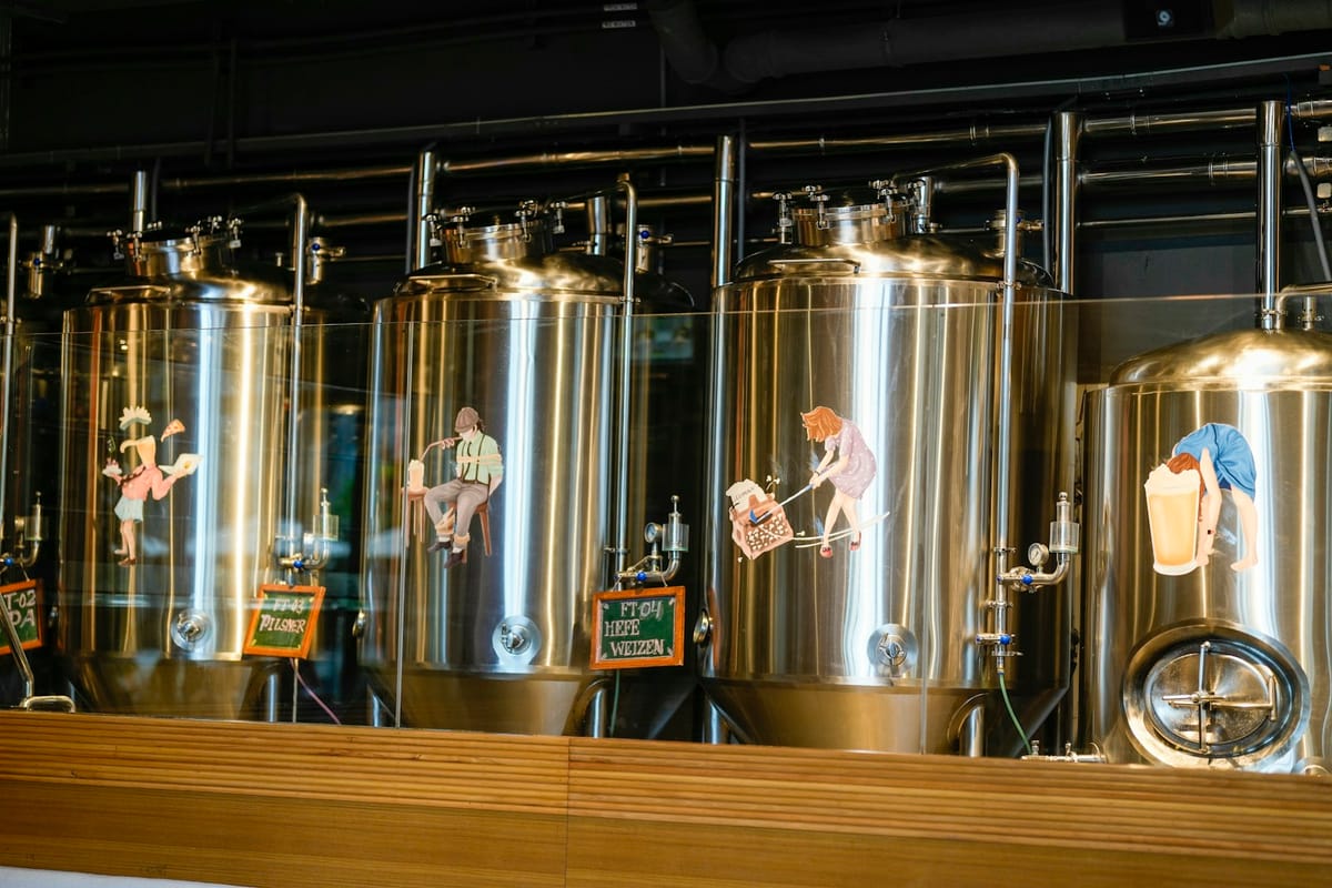 Rows of bright stainless fermentation tanks rising to the exposed timber ceiling of the Iron & Grain brew house