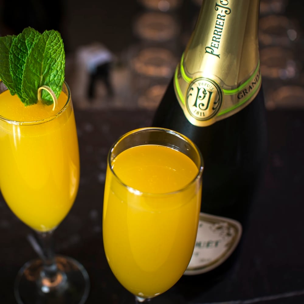 Bottomless mimosas arriving at a sunny window table