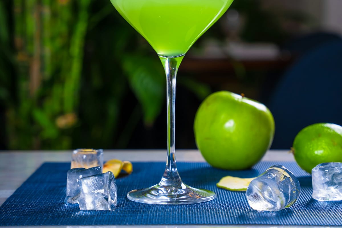 The Emerald Cypher cocktail in a coupe glass — vivid green hue catching the bar light