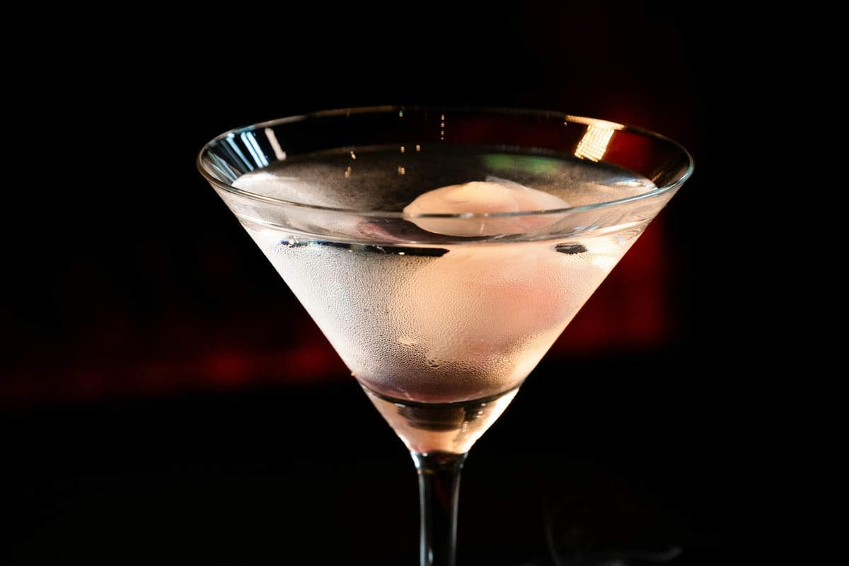 Close-up of the Dead Drop cocktail — deep smoky liquid catching neon light