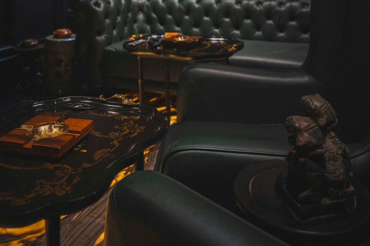 The Velvet Cipher lounge interior — dark low-ceilinged room with tufted green leather seating in low light