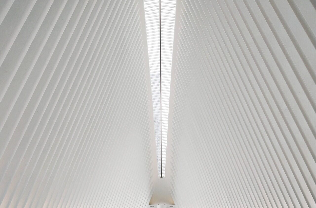 A white ribbed architectural interior converging on a bright vertical slot of daylight
