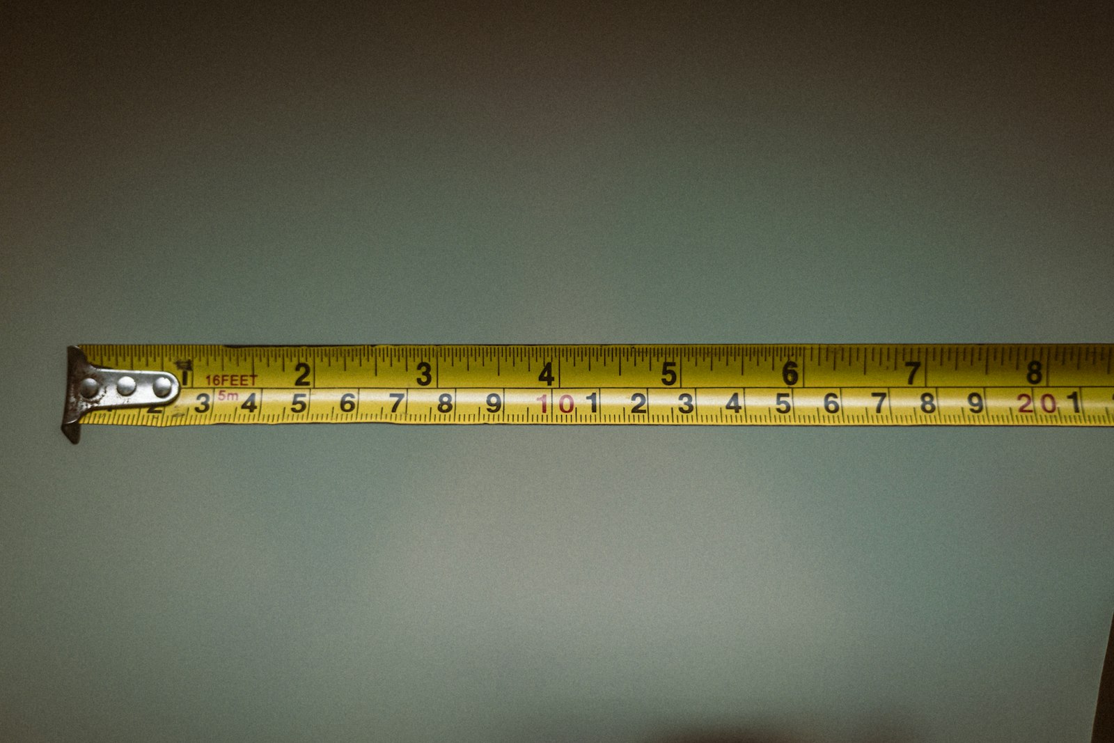 A yellow fabric tailor's tape measure, its markings visible, laid across a plain surface