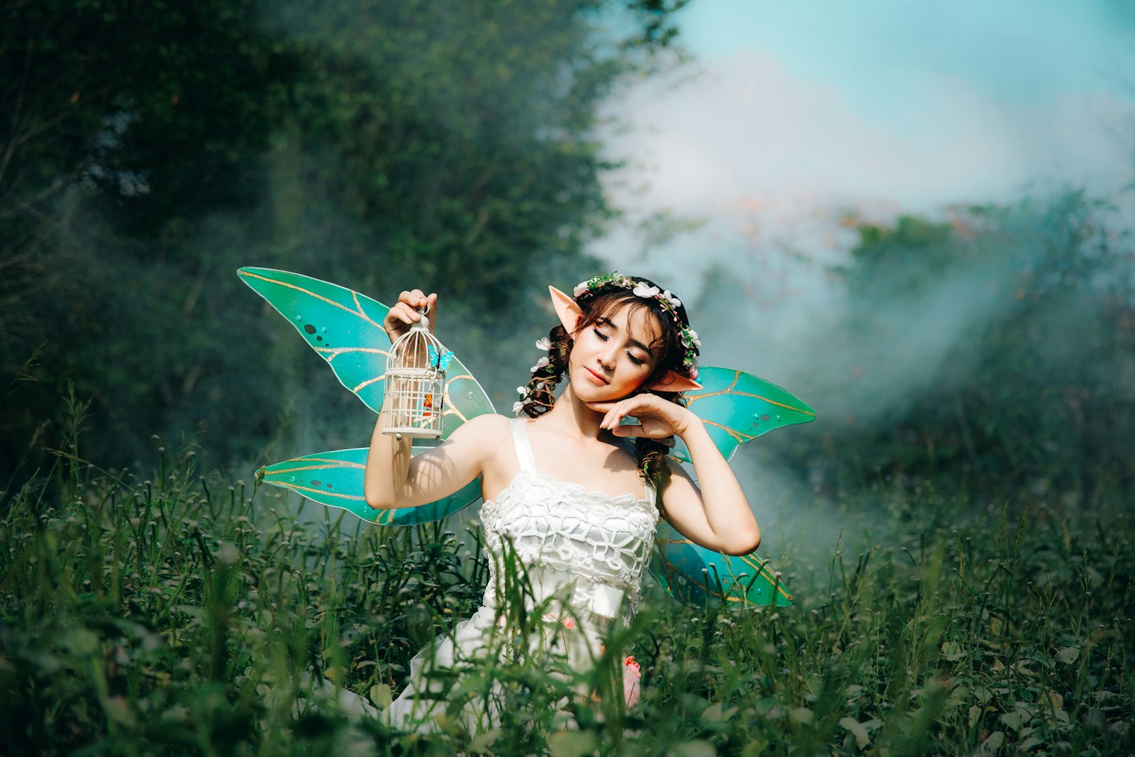 A performer in a fantastical fairy costume with translucent wings, styled for a woodland fairy-court scene