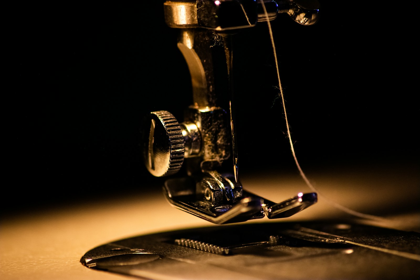 A close-up of a sewing machine's presser foot and needle, threaded, over a piece of fabric