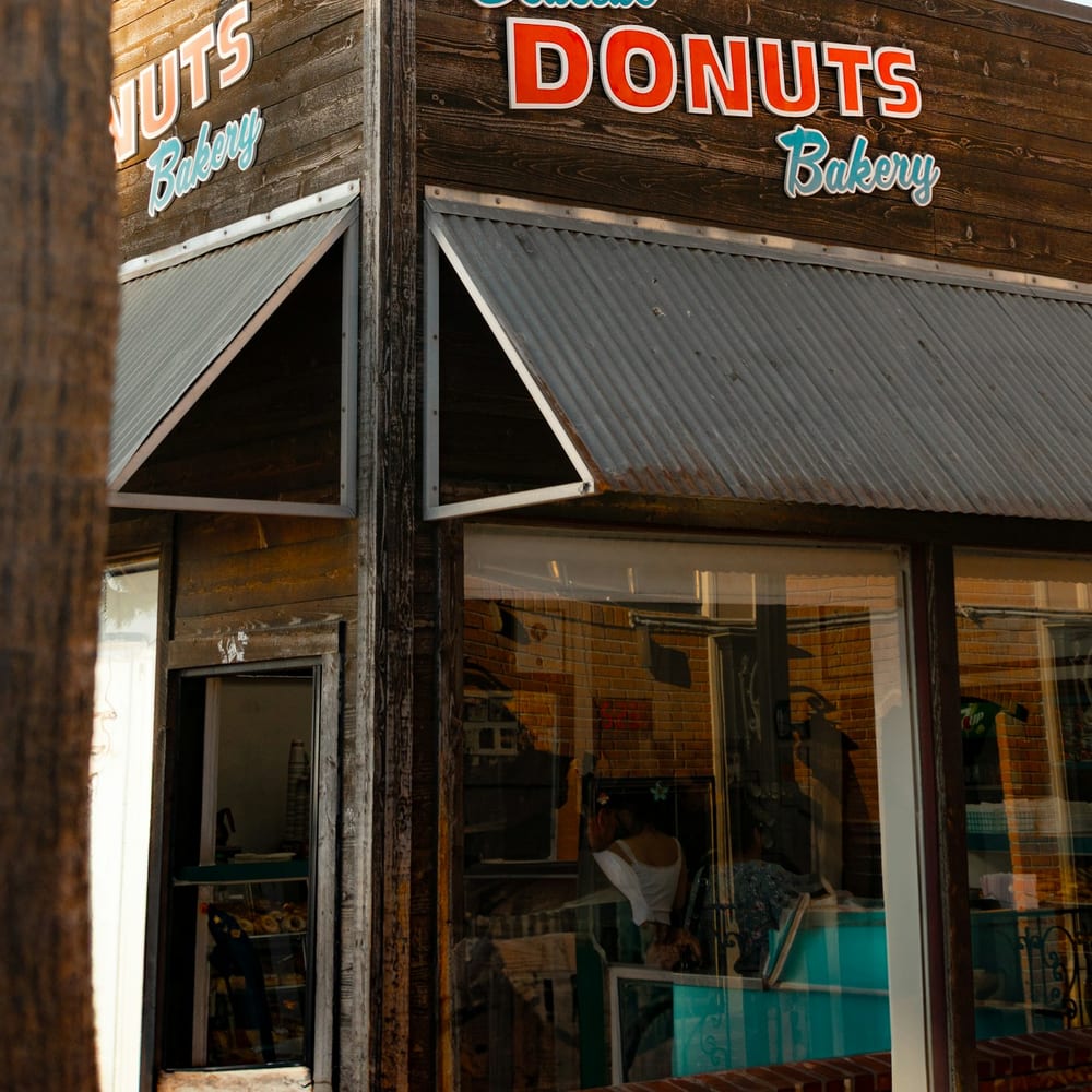 The exterior of Dot's Donuts with its pink awning and hand-lettered sign at morning light