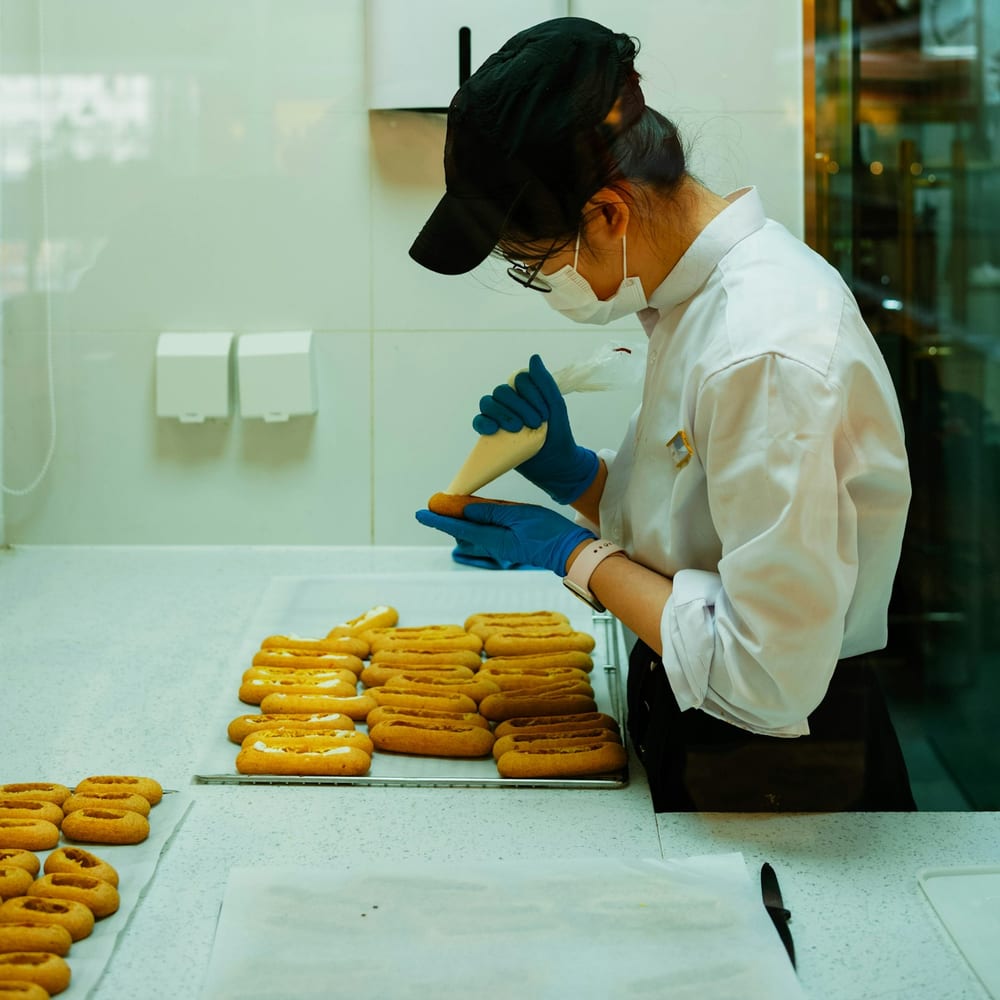 Dot Nguyen piping lemon curd into fresh donuts behind the counter, smiling