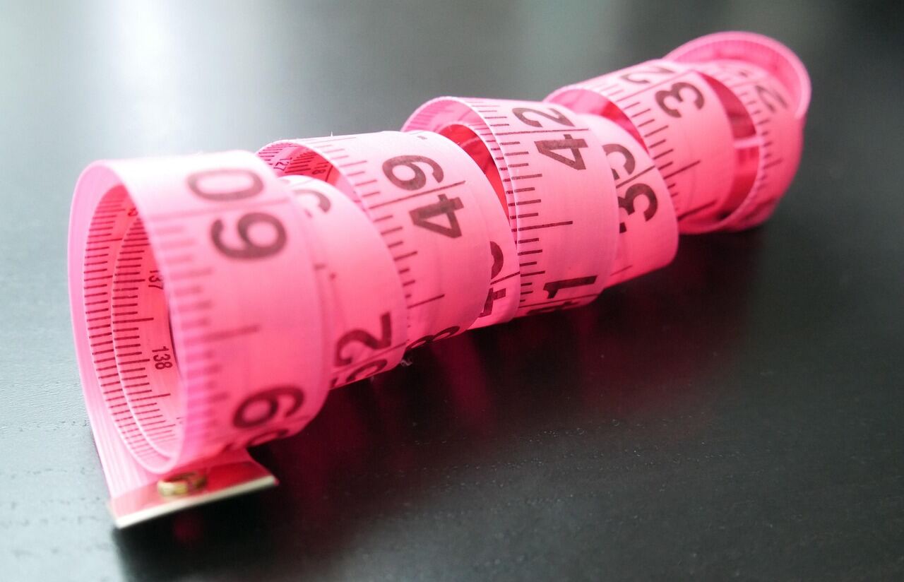 A tailor's tape measure laid across a length of fabric