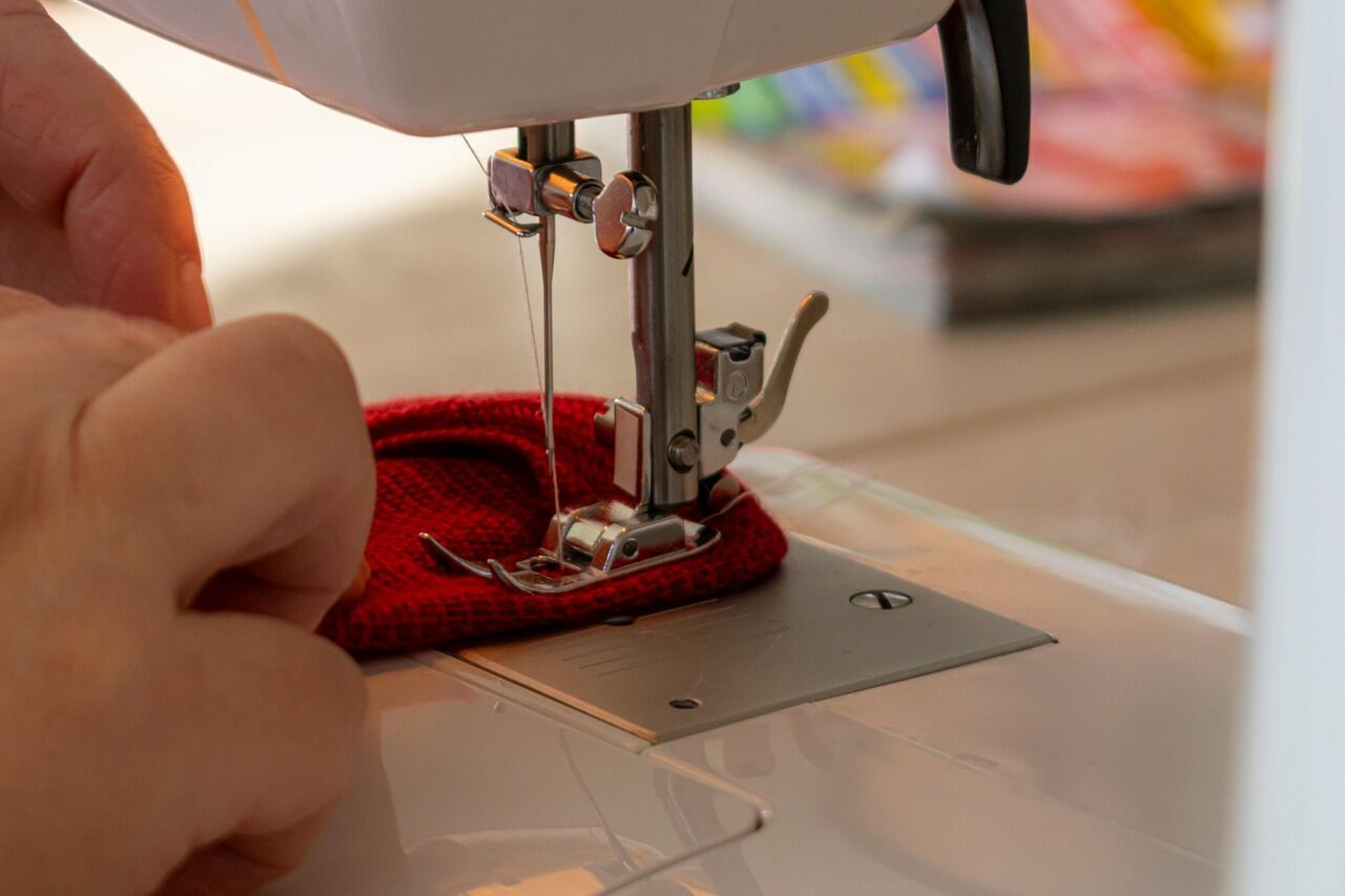 A hand guiding fabric under the needle of a sewing machine