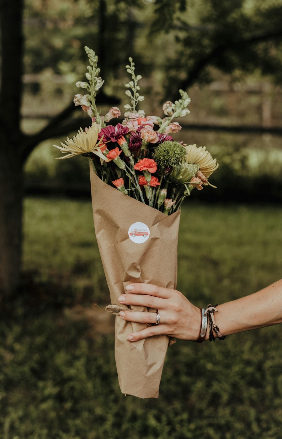 A hand-tied bouquet of snapdragons, chrysanthemums and carnations wrapped in kraft paper