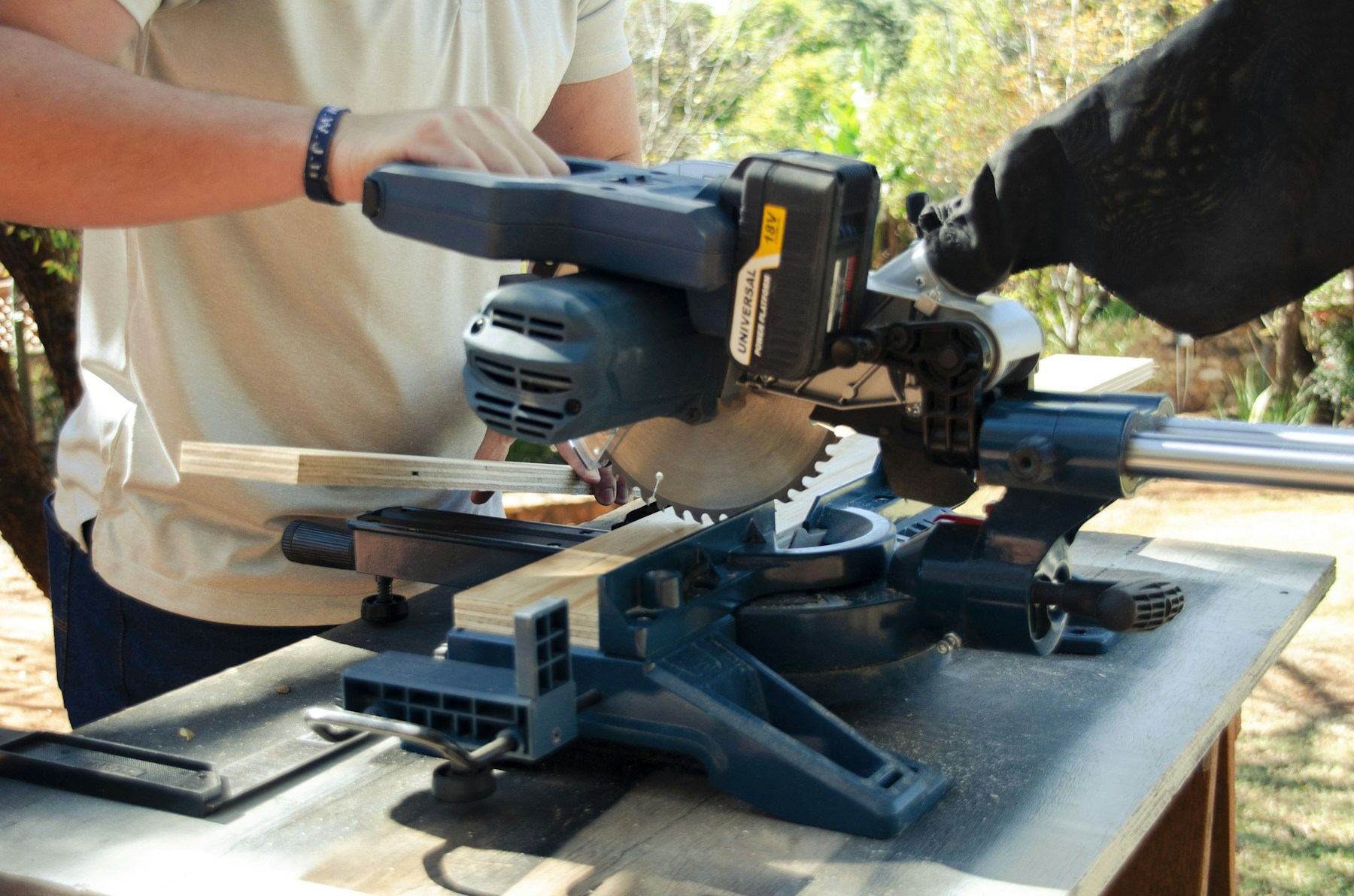 A woodworker guiding a length of stock through a shop saw