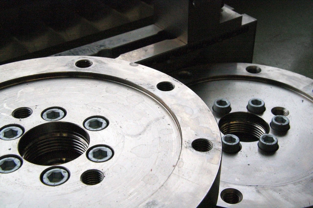Two precision-machined steel mold plates, held in a CNC vise, showing drilled and tapped mounting bores