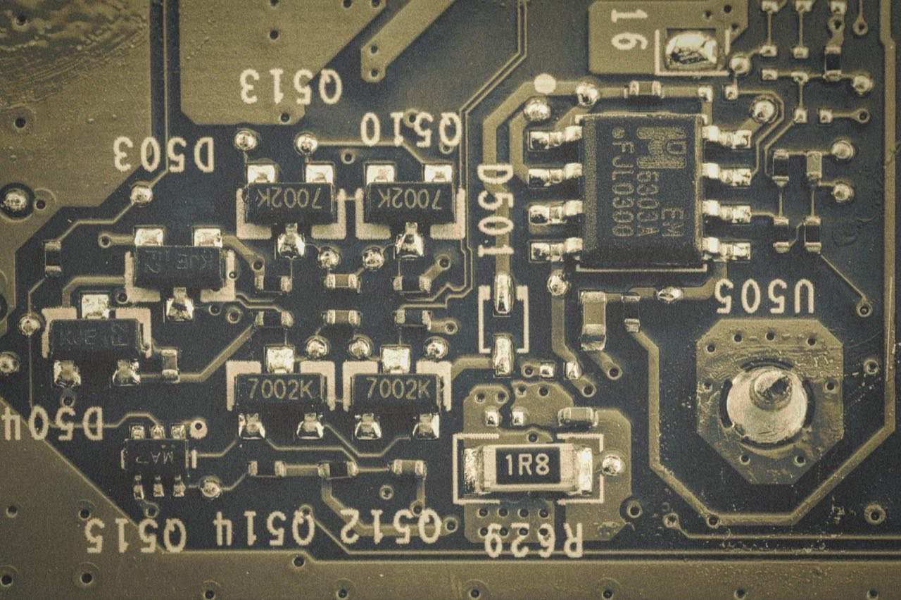 Macro detail of a populated green printed circuit board, showing surface-mount components and trace routing