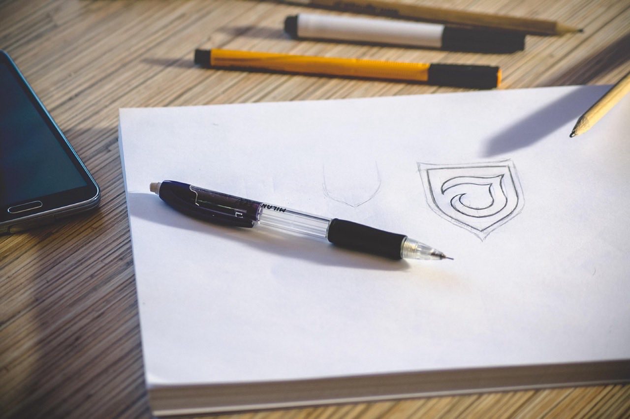 A mechanical pencil resting on a hand-drawn sketch on a studio desk