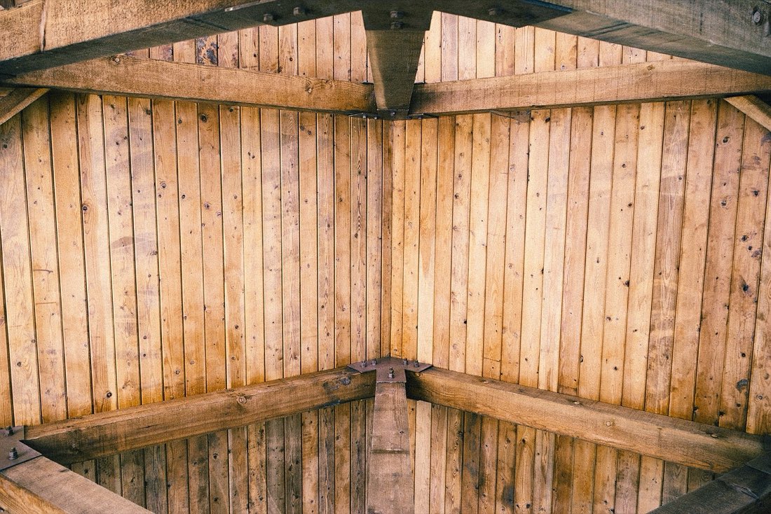 A close-up of an exposed wood-plank ceiling and structural beams