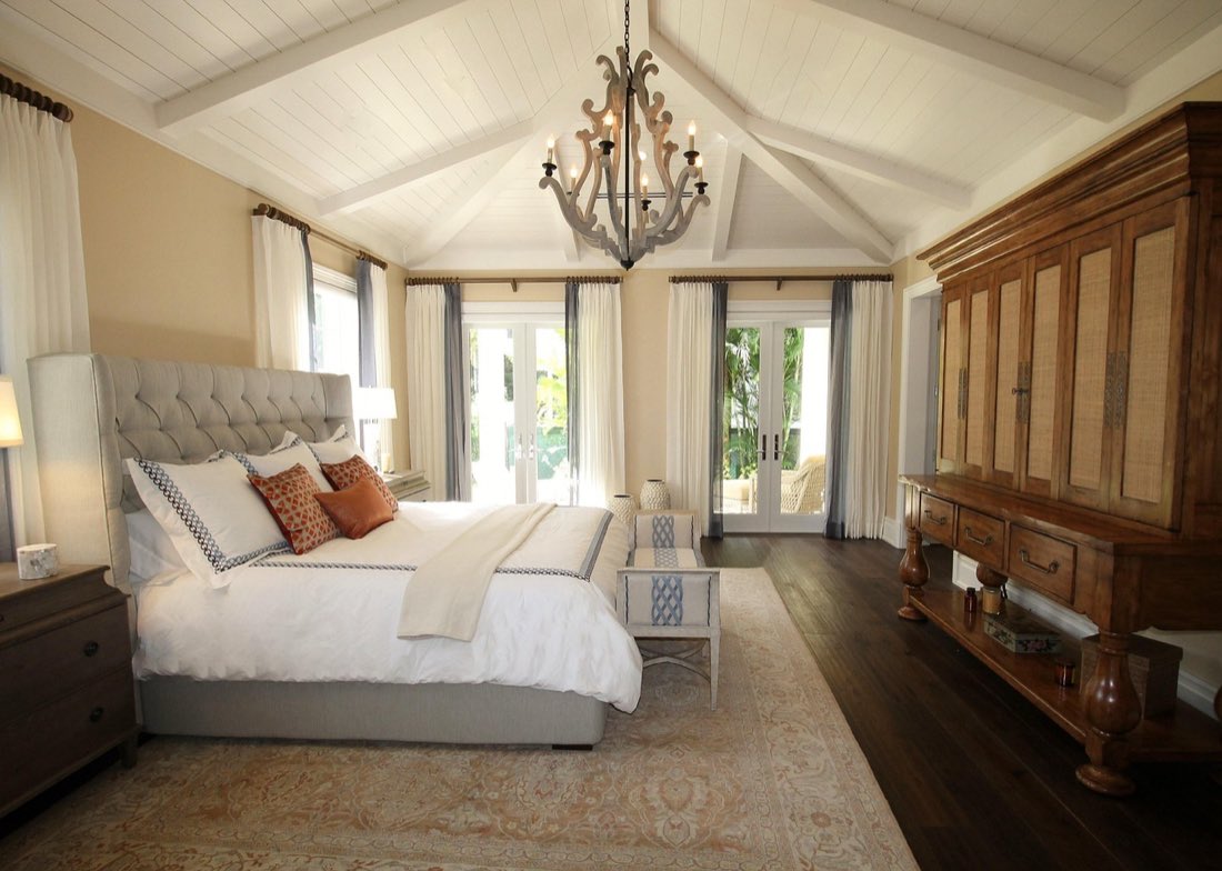 A primary bedroom with a vaulted wood-plank ceiling, exposed beams and a reupholstered headboard